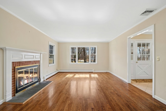 unfurnished living room with baseboards, visible vents, wood finished floors, crown molding, and a fireplace