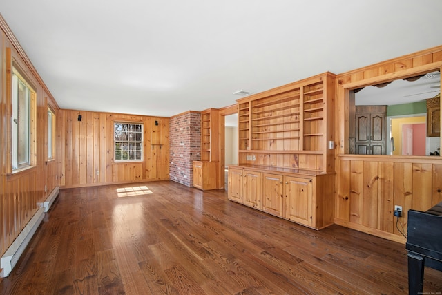 unfurnished living room featuring a baseboard radiator, wooden walls, and dark wood-type flooring