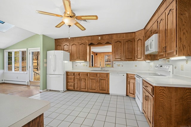 kitchen with white appliances, brown cabinetry, and plenty of natural light