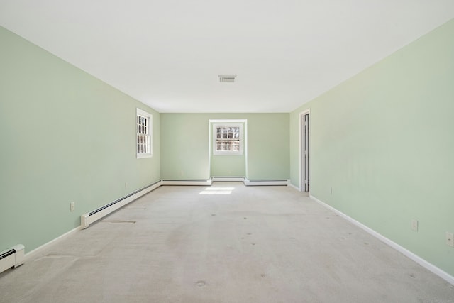 spare room featuring a baseboard heating unit, carpet, and baseboards