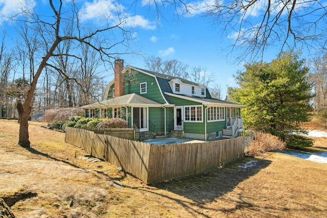 view of front of home featuring a fenced front yard, a sunroom, a shingled roof, and a gambrel roof