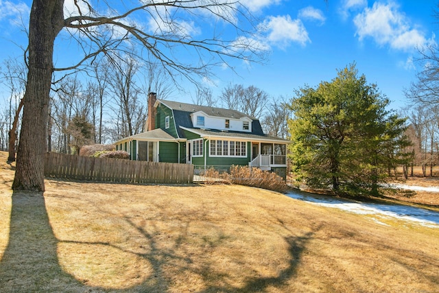 back of property featuring dirt driveway, a gambrel roof, a chimney, fence, and a porch