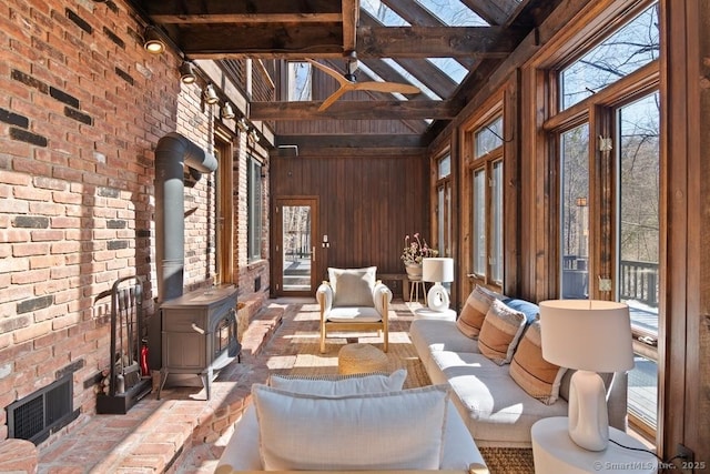 interior space with visible vents, vaulted ceiling with beams, a wood stove, and a ceiling fan