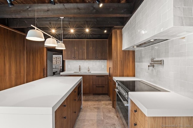 kitchen featuring tasteful backsplash, a kitchen island, light countertops, stainless steel stove, and a sink