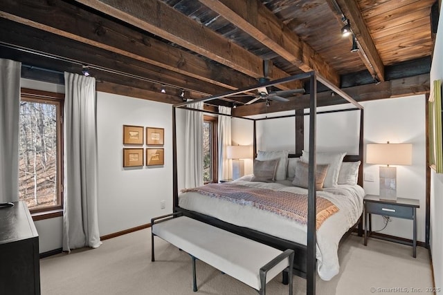 carpeted bedroom featuring wood ceiling, beam ceiling, rail lighting, and baseboards