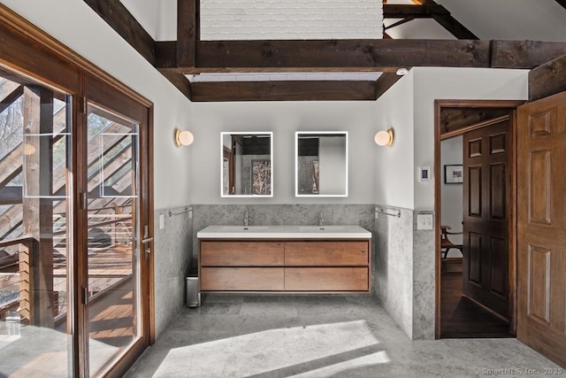 bathroom featuring tile walls, wainscoting, beamed ceiling, and vanity