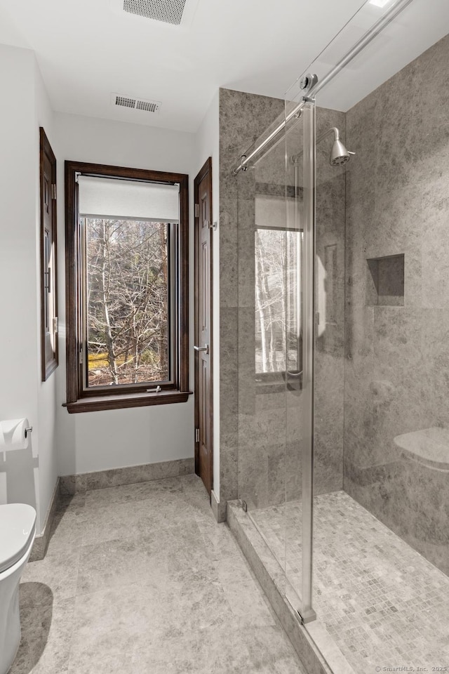 bathroom featuring toilet, a shower stall, visible vents, and baseboards