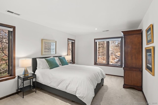 bedroom with baseboards, visible vents, and light colored carpet