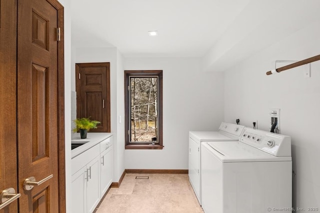 clothes washing area with cabinet space, baseboards, and washer and clothes dryer