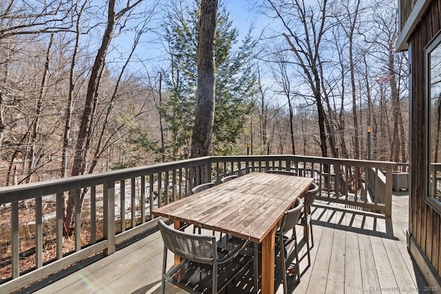 wooden terrace with a forest view and outdoor dining space