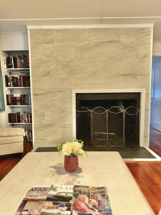 interior details featuring crown molding, a tiled fireplace, and wood finished floors