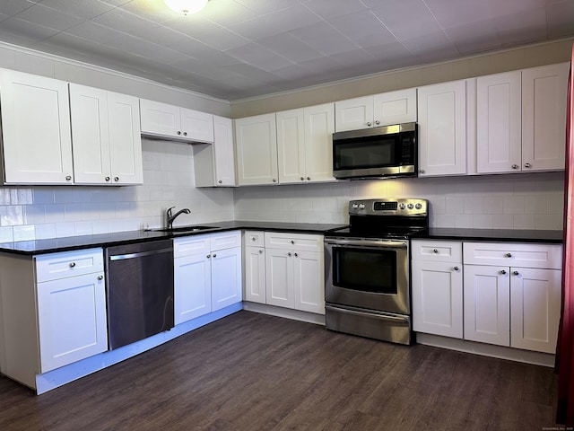 kitchen featuring dark countertops, dark wood-style flooring, stainless steel appliances, white cabinetry, and a sink