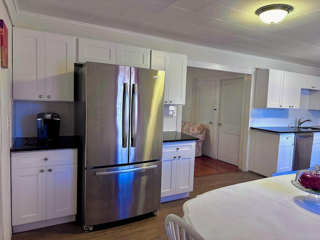 kitchen featuring white cabinets, dark countertops, dark wood-type flooring, stainless steel appliances, and a sink