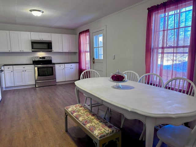 kitchen featuring stainless steel appliances, dark countertops, wood finished floors, and white cabinets