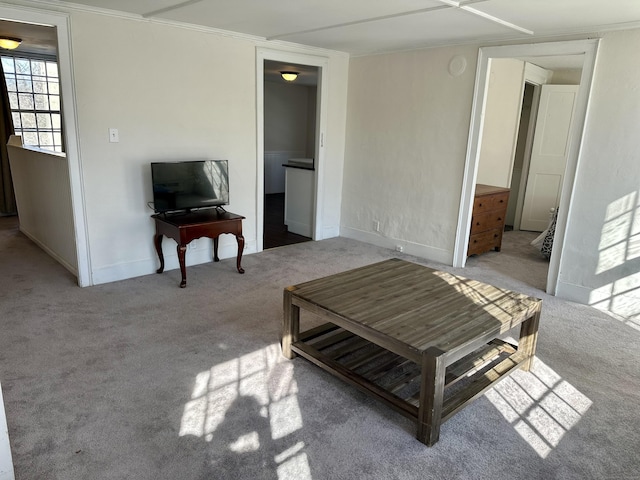 living area with light carpet, baseboards, and crown molding