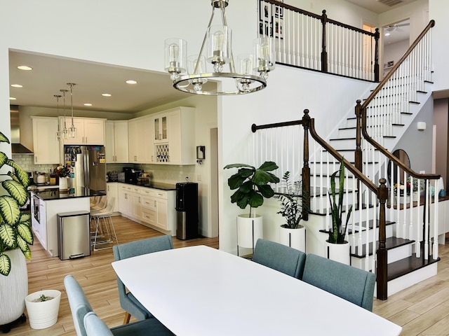 dining room featuring an inviting chandelier, light wood-style flooring, stairs, and recessed lighting