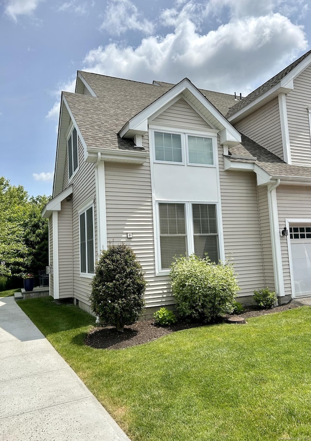 view of property exterior with a shingled roof and a yard