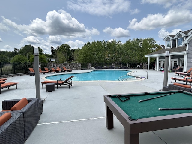 community pool with a patio area and fence