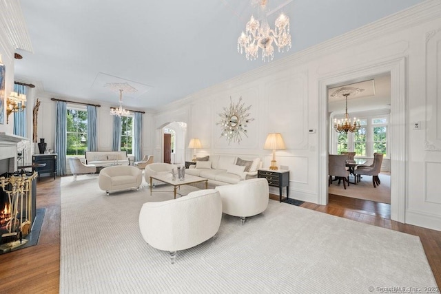 living area with a chandelier, arched walkways, a decorative wall, and plenty of natural light