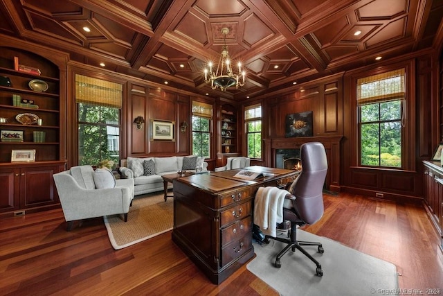 office area with built in shelves, plenty of natural light, and wood walls