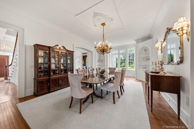 dining area featuring crown molding, stairs, a chandelier, and wood finished floors