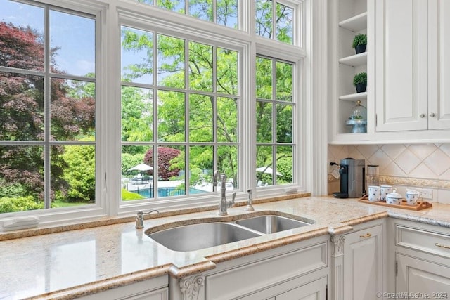 kitchen with plenty of natural light, white cabinets, and a sink