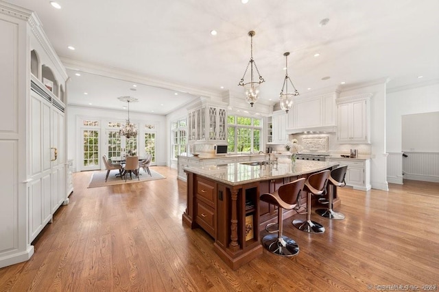 kitchen with hanging light fixtures, a spacious island, glass insert cabinets, and white cabinets