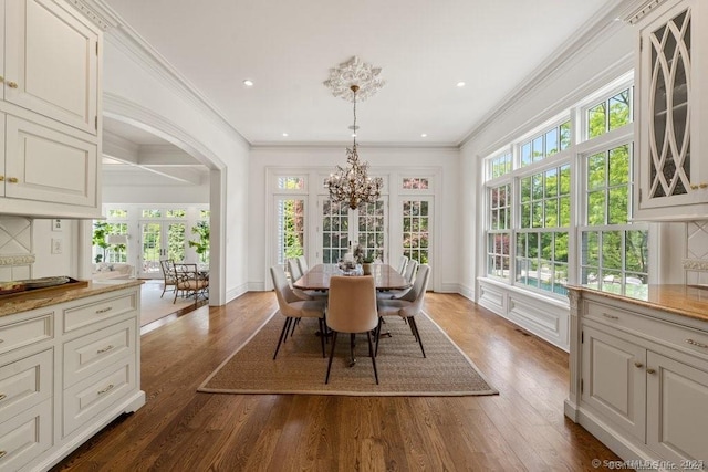 dining area with dark wood-style floors, a notable chandelier, crown molding, and baseboards