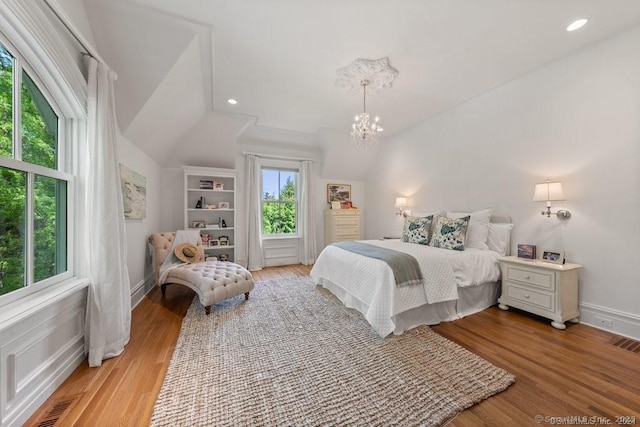 bedroom with light wood-type flooring, lofted ceiling, recessed lighting, and an inviting chandelier