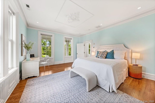 bedroom featuring light wood-style flooring, visible vents, and crown molding