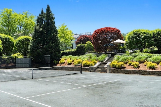 view of tennis court with stairs and fence