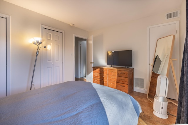 bedroom with a closet, wood finished floors, and visible vents