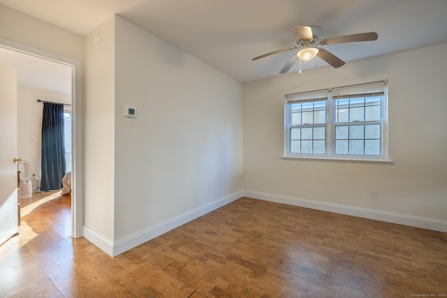 spare room with ceiling fan, light wood-type flooring, and baseboards