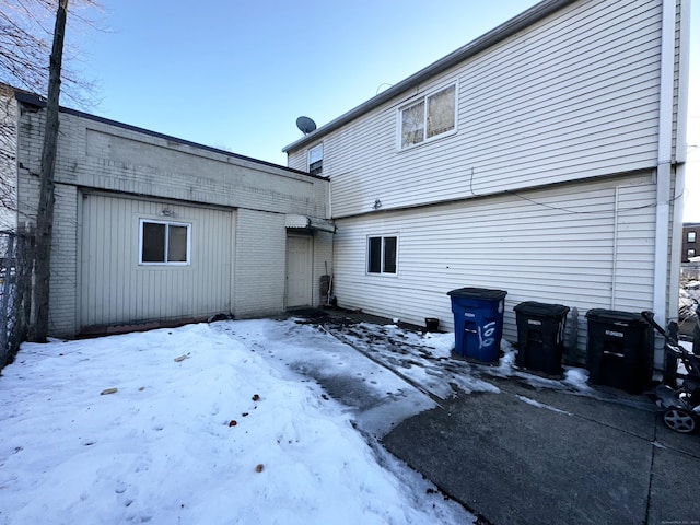 snow covered rear of property featuring brick siding