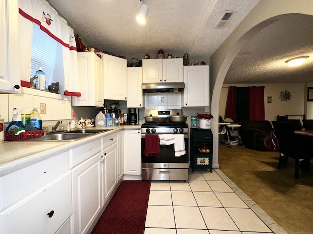 kitchen with light countertops, stainless steel gas range oven, white cabinetry, and under cabinet range hood