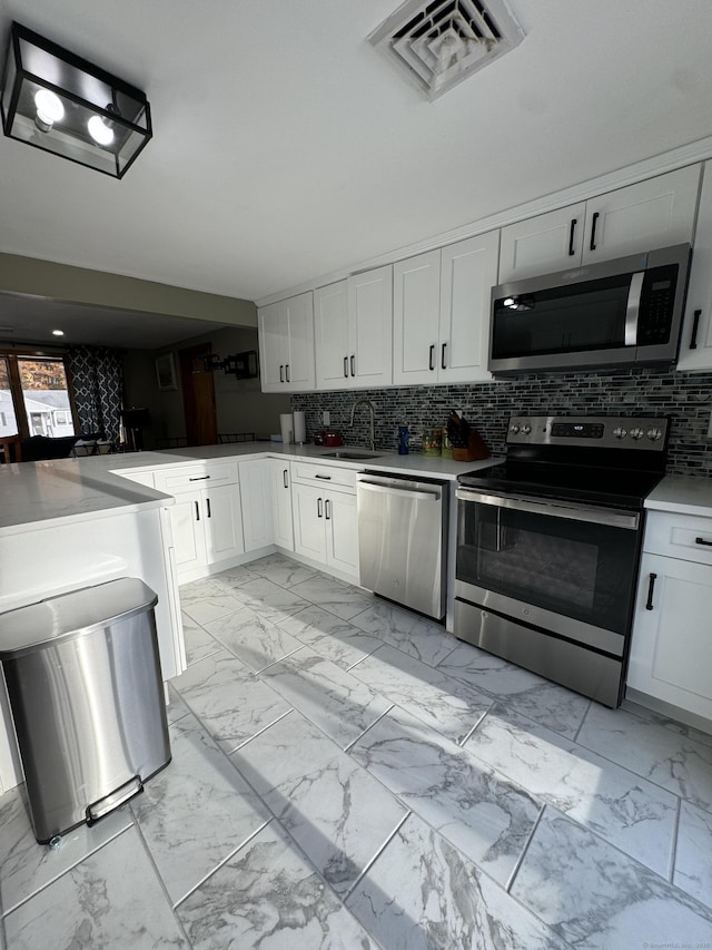 kitchen featuring marble finish floor, stainless steel appliances, tasteful backsplash, visible vents, and a sink