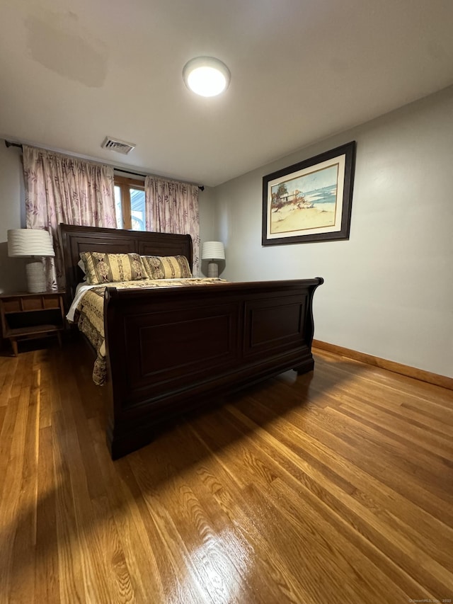 bedroom with visible vents, baseboards, and wood finished floors