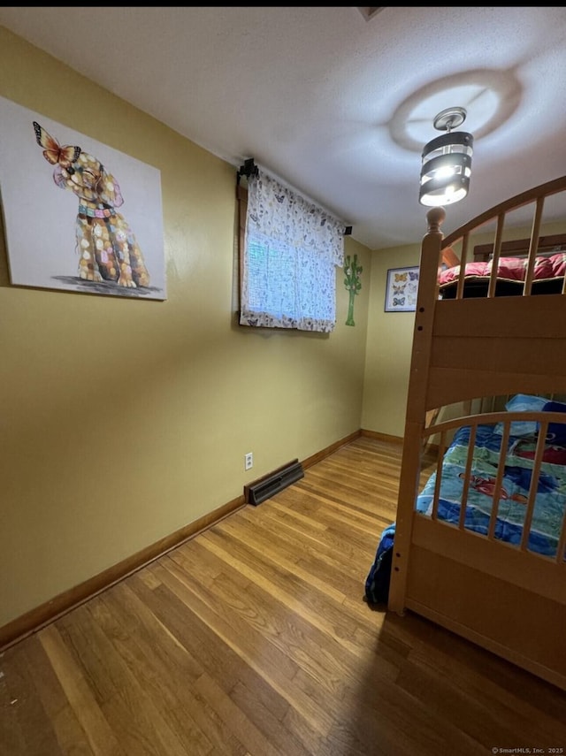 unfurnished bedroom with wood finished floors, visible vents, and baseboards