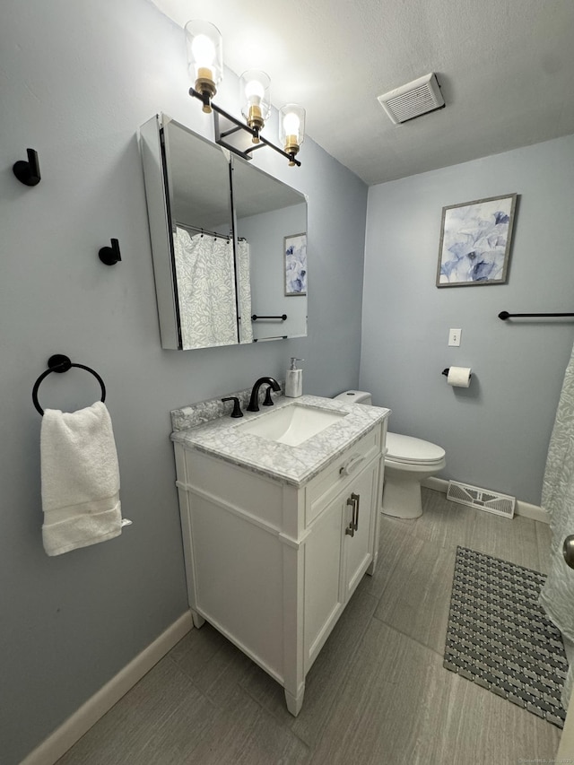 full bath featuring toilet, vanity, visible vents, and baseboards