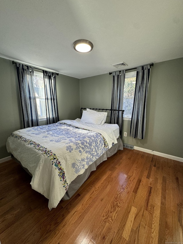 bedroom featuring wood finished floors, visible vents, and baseboards