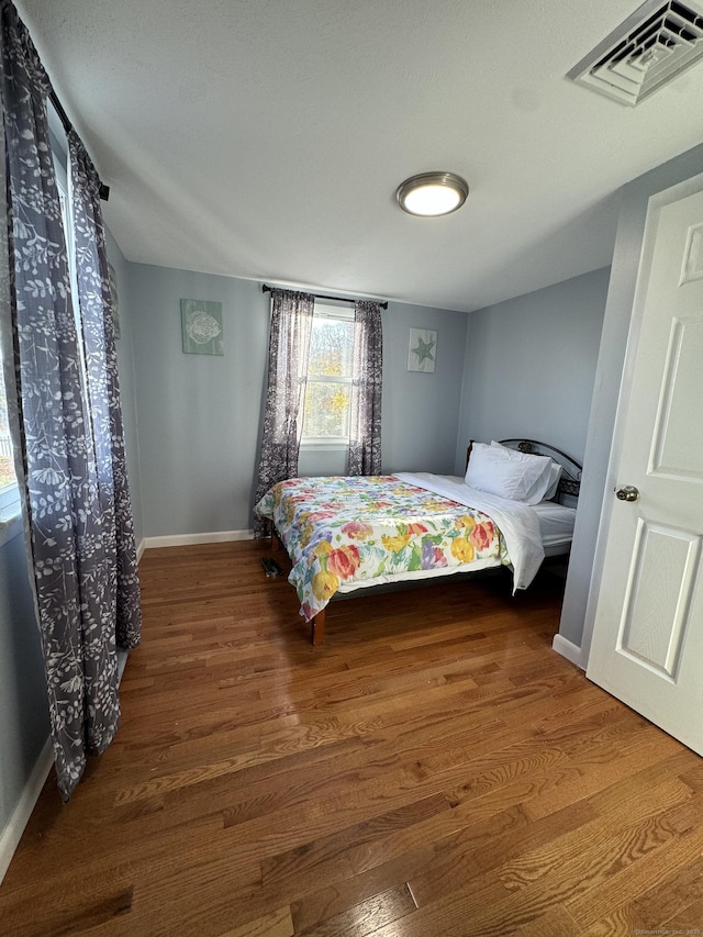 bedroom featuring baseboards, visible vents, and wood finished floors