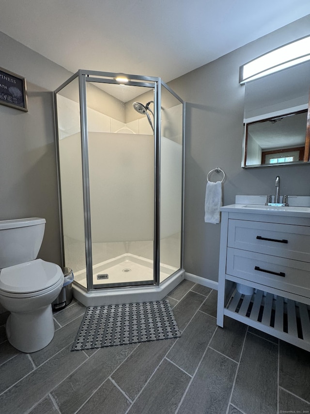 bathroom featuring a stall shower, baseboards, vanity, and toilet