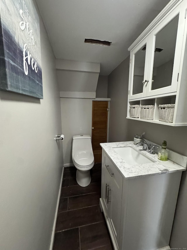 bathroom featuring wood finish floors, toilet, vanity, and baseboards