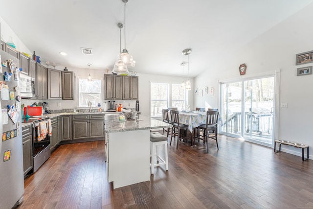 kitchen with a center island, pendant lighting, a breakfast bar, stainless steel appliances, and visible vents