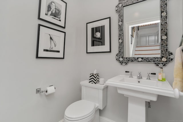 bathroom with baseboards, a sink, and toilet