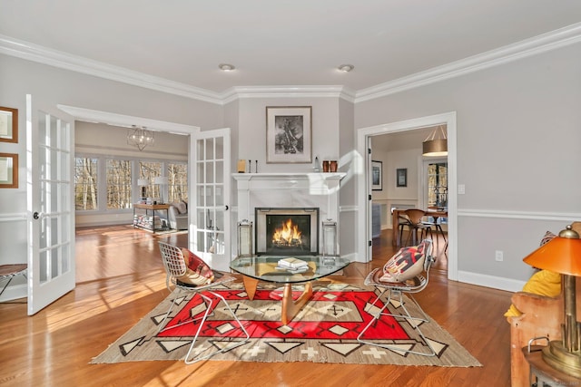 living room with french doors, a premium fireplace, ornamental molding, wood finished floors, and baseboards