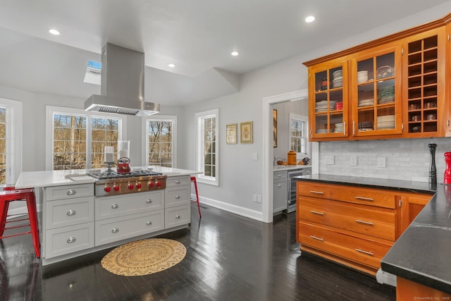 kitchen with tasteful backsplash, baseboards, dark wood-style flooring, extractor fan, and stainless steel gas stovetop