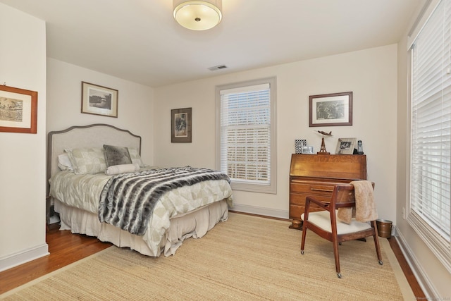 bedroom featuring visible vents, light wood-style flooring, baseboards, and multiple windows