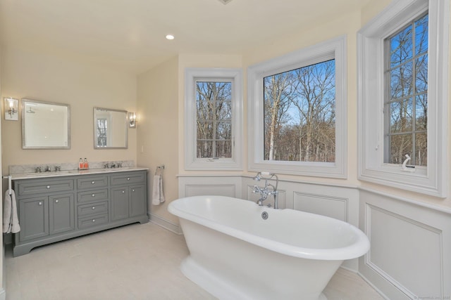 bathroom with a soaking tub, a decorative wall, a sink, and double vanity