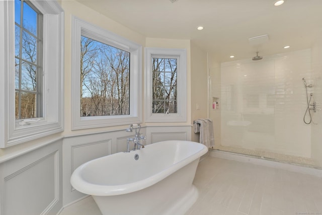 full bathroom featuring recessed lighting, a soaking tub, a decorative wall, a stall shower, and wainscoting